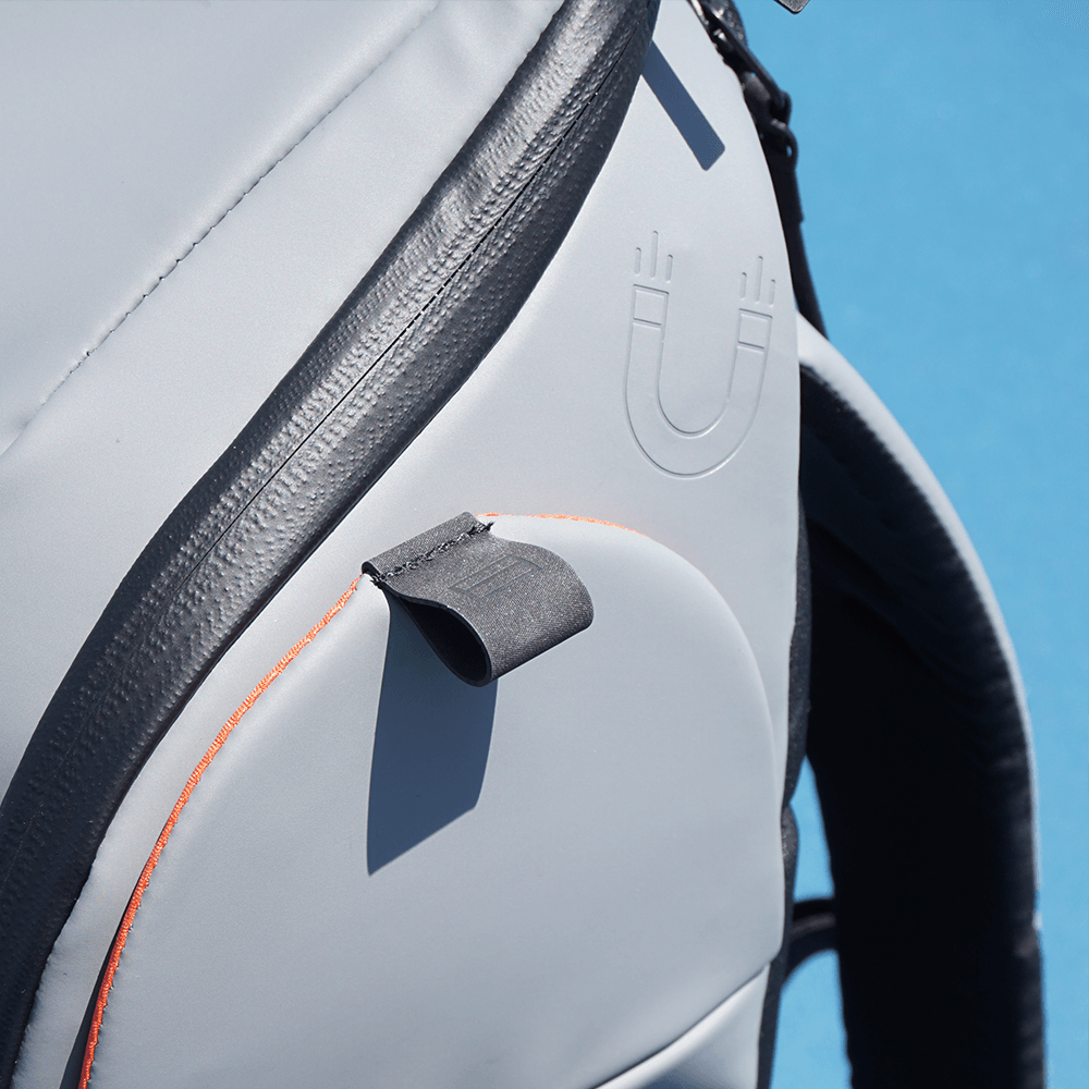 Close-up of a gray and black backpack with an embossed magnet symbol.