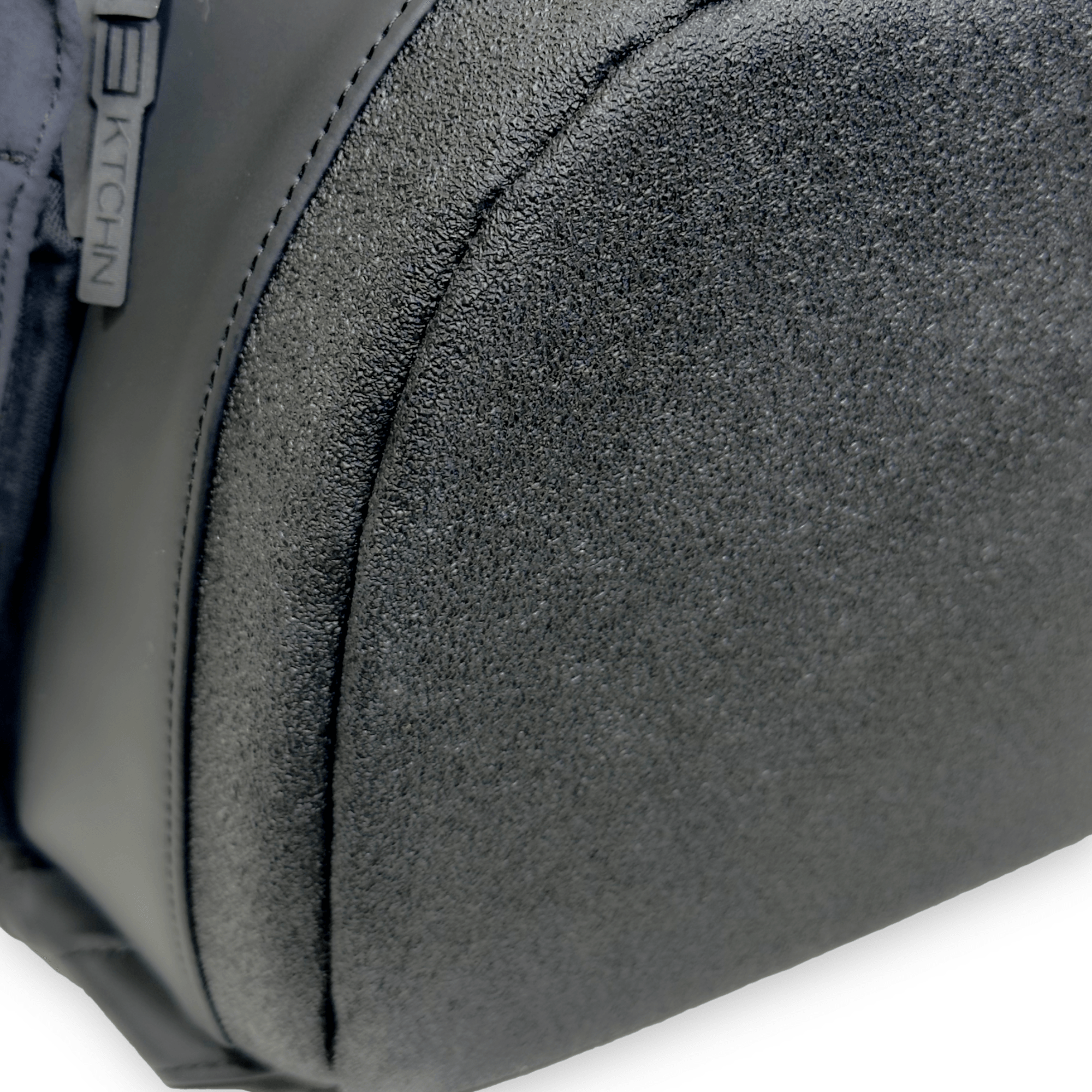 Close-up of a textured black-coloured fabric bag with zipper pull tab.